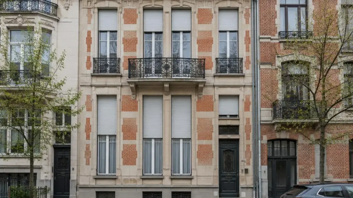 Rangée de hautes fenêtres à volets roulants sur une façade éclectique de Saint-Gilles